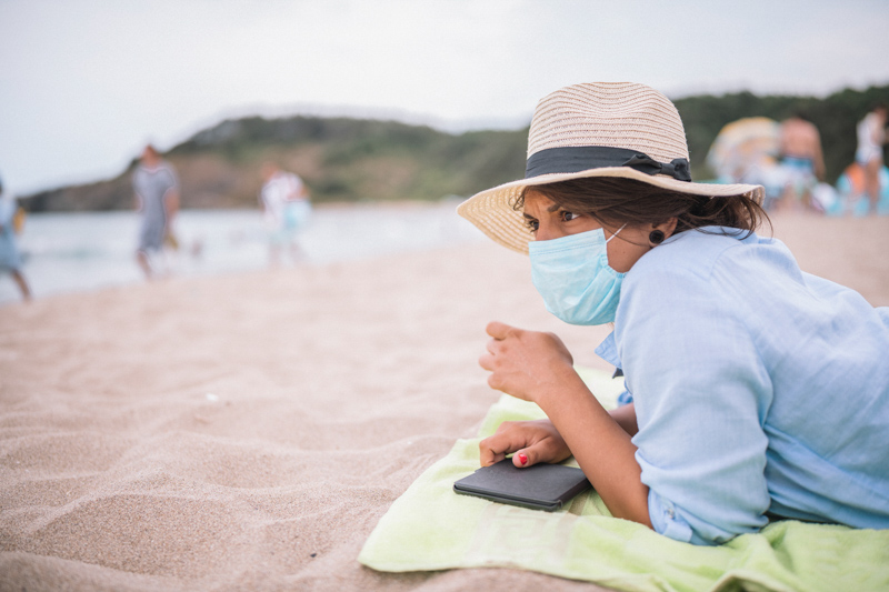 woman with protective face mask on the beach