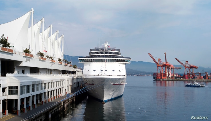 The Carnival Spirit cruise ship sits docked at Canada Place as a seabus (R) commuter boat makes its way across the inner